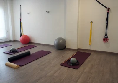 Vista general de la sala de pilates con colchonetas burdeos y material de entrenamiento distribuido.