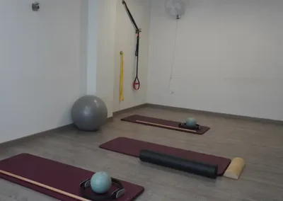 Sala de pilates con colchonetas, pelotas y correas de suspensión en pared