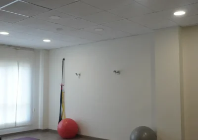 Sala de pilates con colchonetas y pelotas, con luces del techo visibles