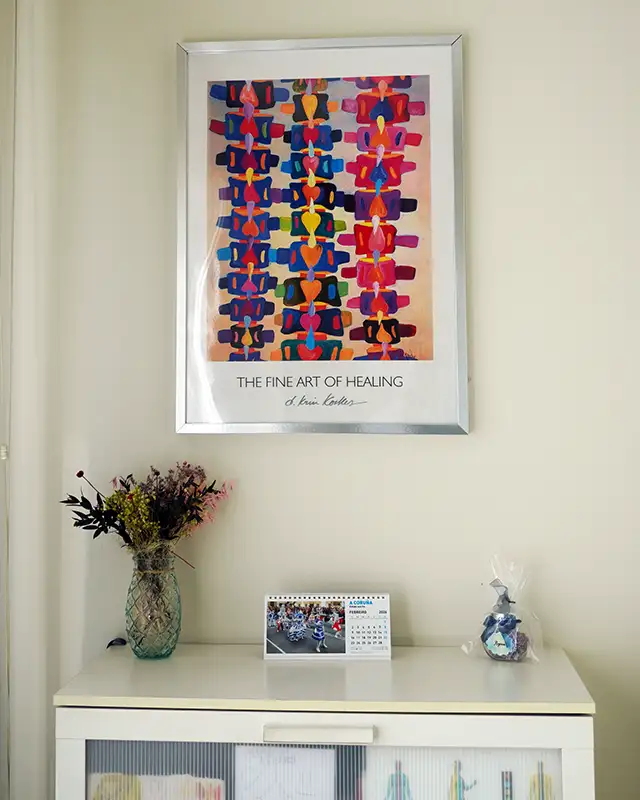 Rincón de sala clínica con cuadro decorativo, flores y mobiliario auxiliar.