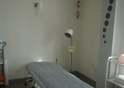 Rincón de sala clínica con cuadro decorativo, flores y mobiliario auxiliar.