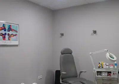 Gabinete de podología con sillón especializado y lámpara de aumento.