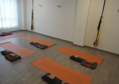 Espacio de clases colectivas con esterillas naranjas y material de apoyo