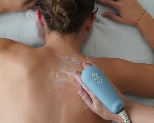 Tratamiento de radiofrecuencia en la espalda de un paciente usando un dispositivo médico manual.